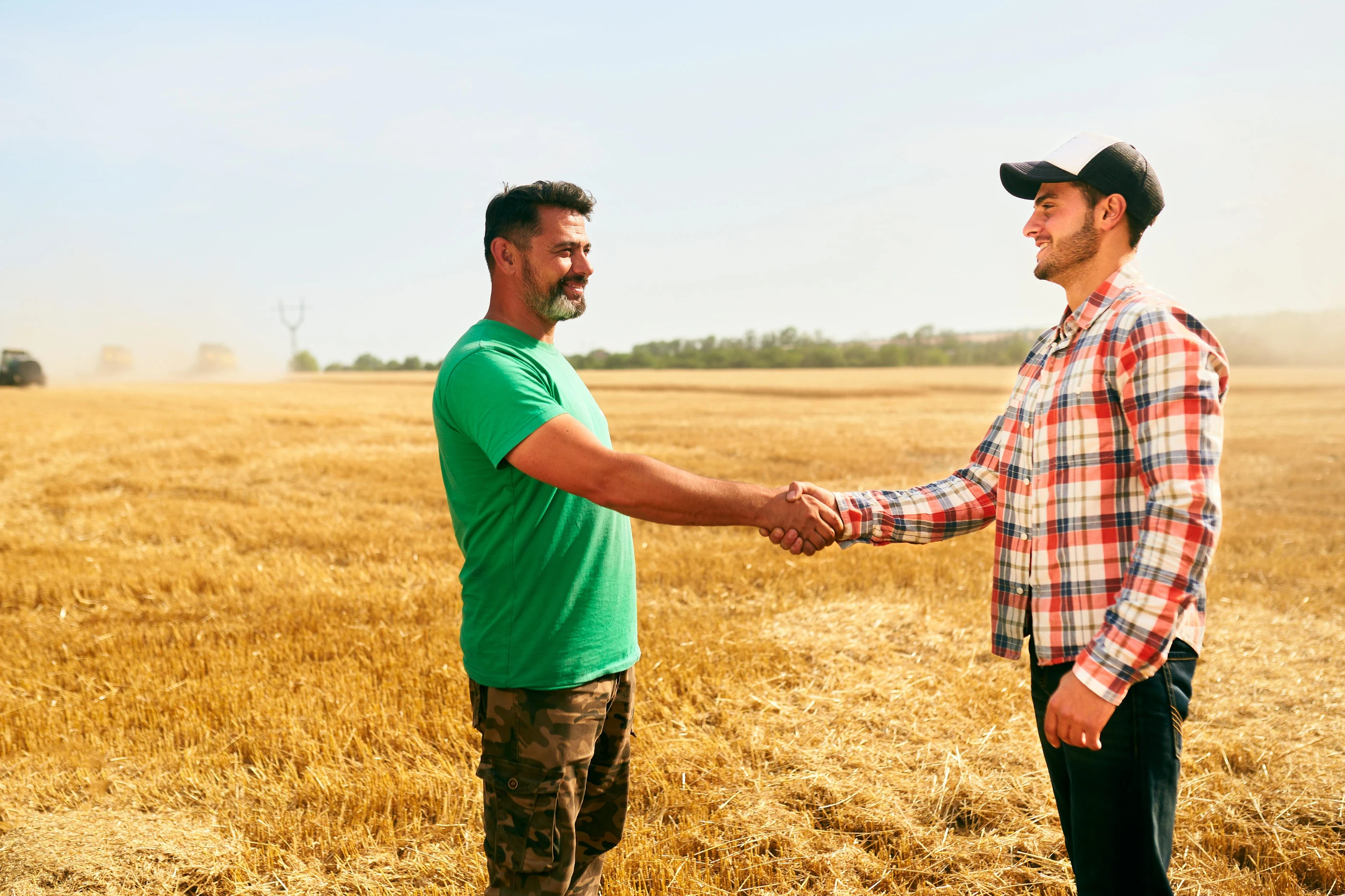 Dans un champ de céréales, deux personnes, dont l'agriculteur se serrent la main